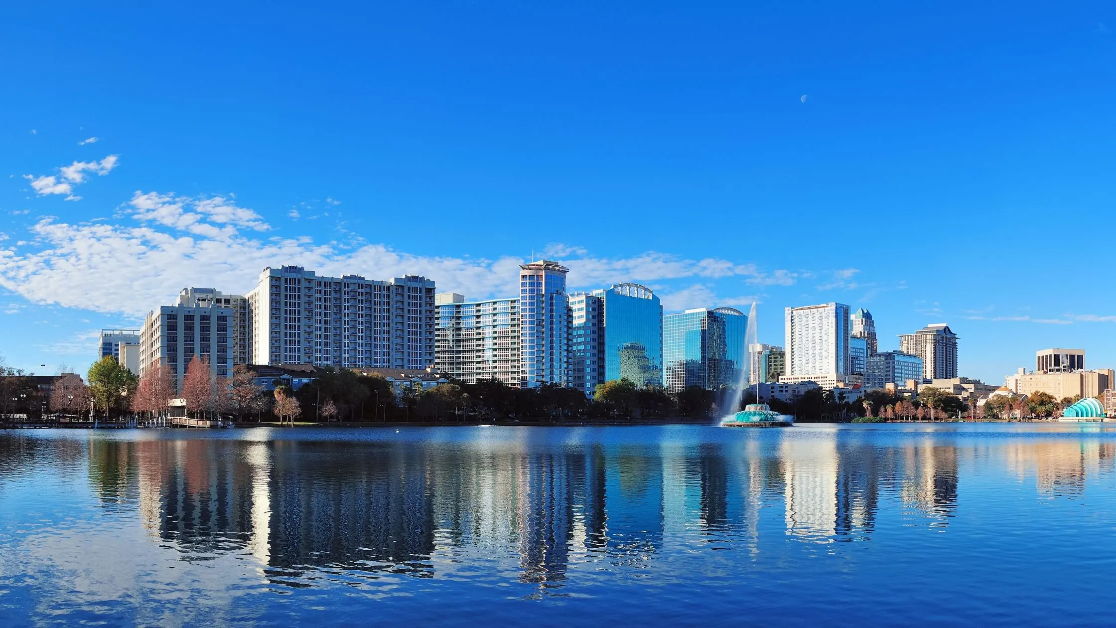 Landscape de Orlando, 10 edificios altos, reflejados en el lago Eola y arriba un cielo celeste sin nubes