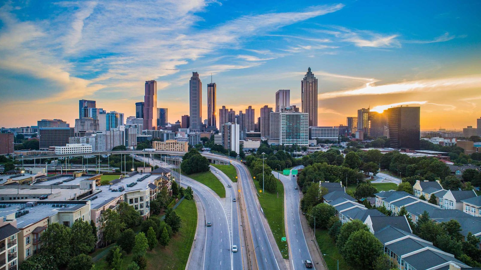 Se ve 3 lineas de autopista con el skyline de Atlanta al fondo. Un cielo celeste fuerte con nubes esfumadas.
