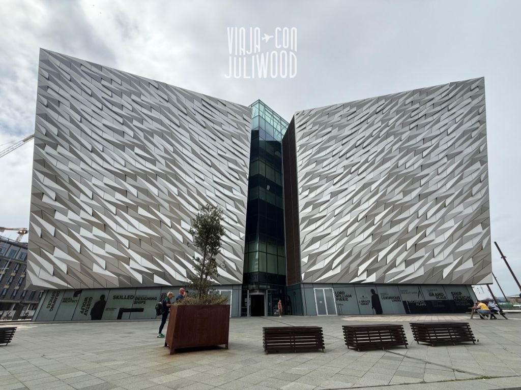 Fachada moderna del museo Titanic Belfast con diseño metálico en forma de proa de barco, bajo un cielo nublado.
