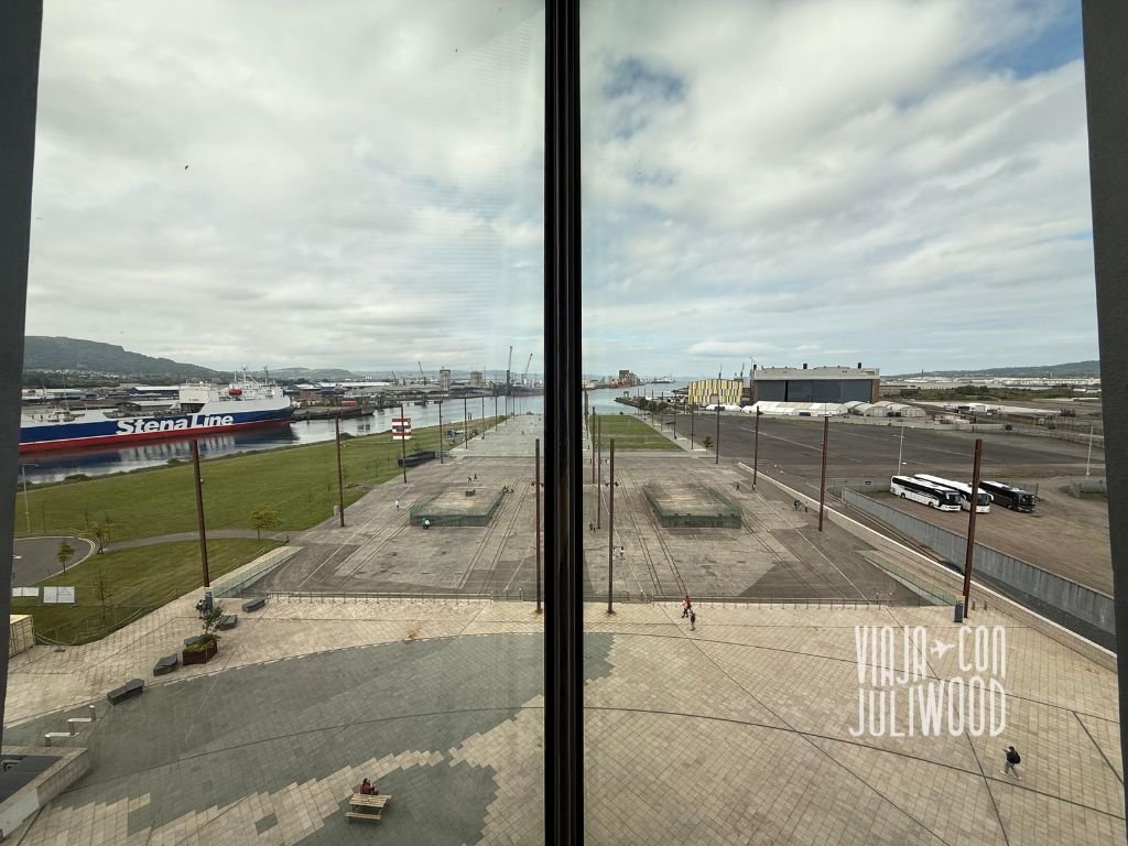 Vista panorámica del astillero de Belfast desde una ventana del museo, con el puerto, grúas y el mar de fondo.
