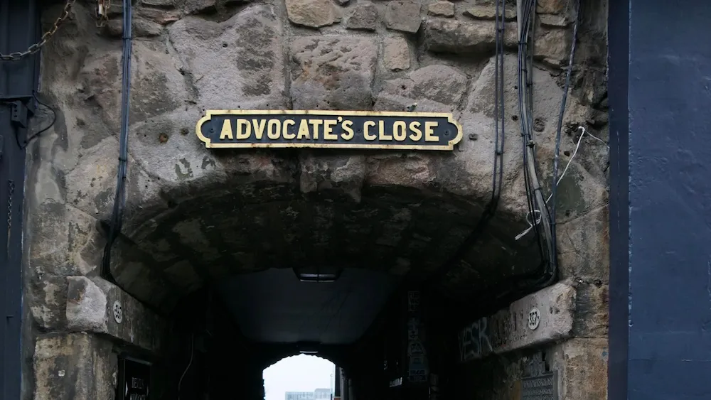 Entrada de piedra con cartel que dice “Advocate’s Close”, un pasaje histórico en Edimburgo, Escocia.