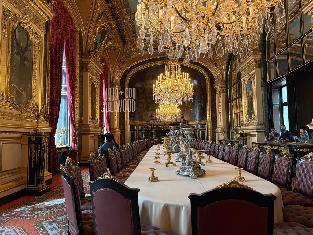Sala del comedor de los Aposentos de Napoleón en el Louvre, con una larga mesa ovalada, arañas de cristal y decoración dorada.