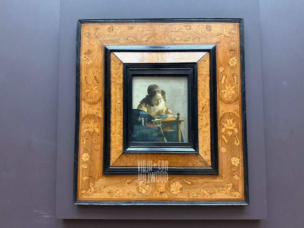 Cuadro “La encajera” de Johannes Vermeer en el Louvre, una mujer concentrada trabajando sobre encajes en un pequeño lienzo.