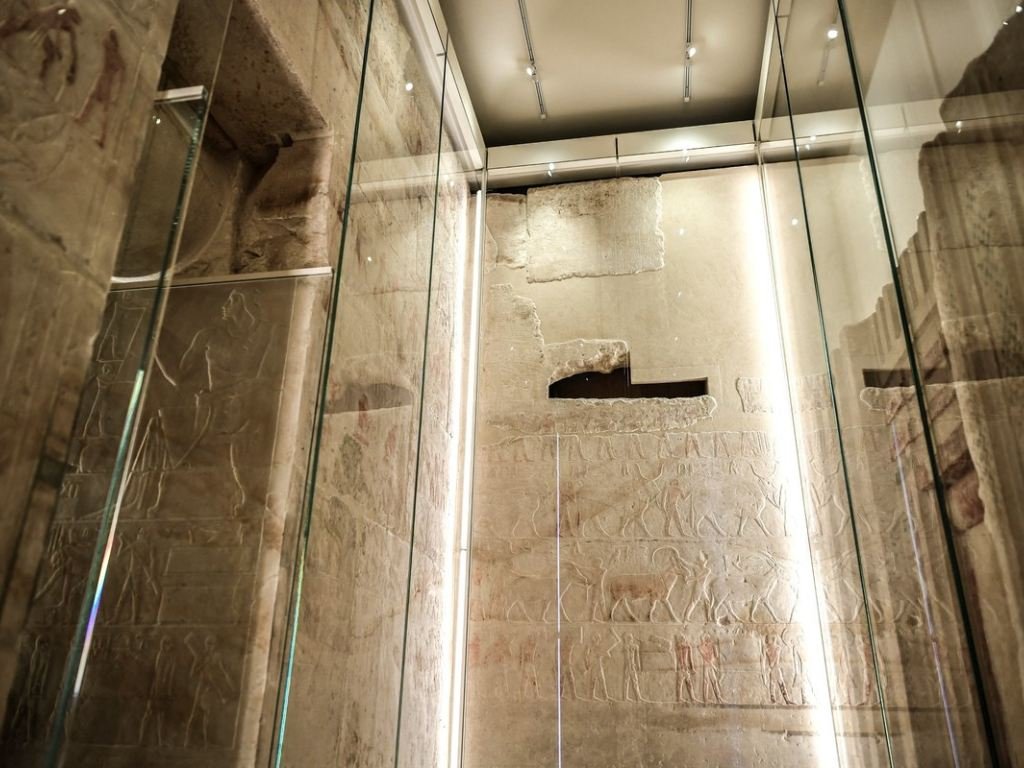 Relieves originales de la capilla funeraria de Akhethotep en el Louvre, protegidos por vitrinas de vidrio y decorados con escenas del Antiguo Egipto.