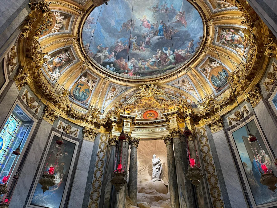 Detalle del interior de la iglesia Saint-Sulpice en París, con una cúpula pintada, columnas de mármol y ornamentos dorados.