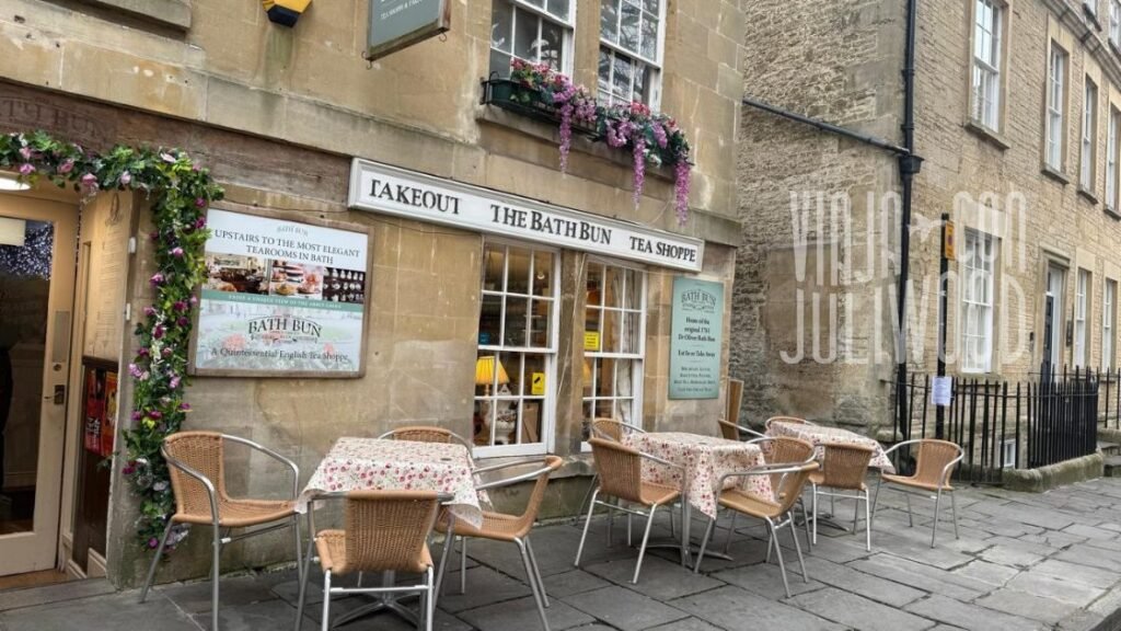 Fachada de Sally Lunn’s Historic Eating House en Abbey Green, una casa de té tradicional con mesas exteriores, sillas de mimbre y carteles antiguos en las ventanas.