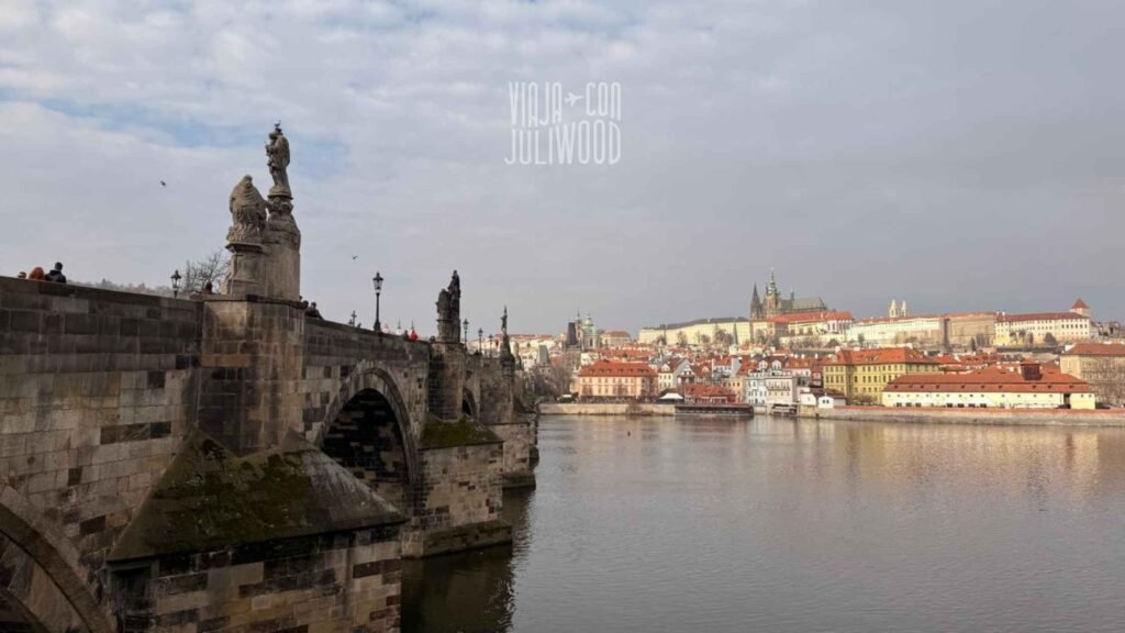 Puente de Carlos en Praga con esculturas y vista al castillo y al río Moldava.
