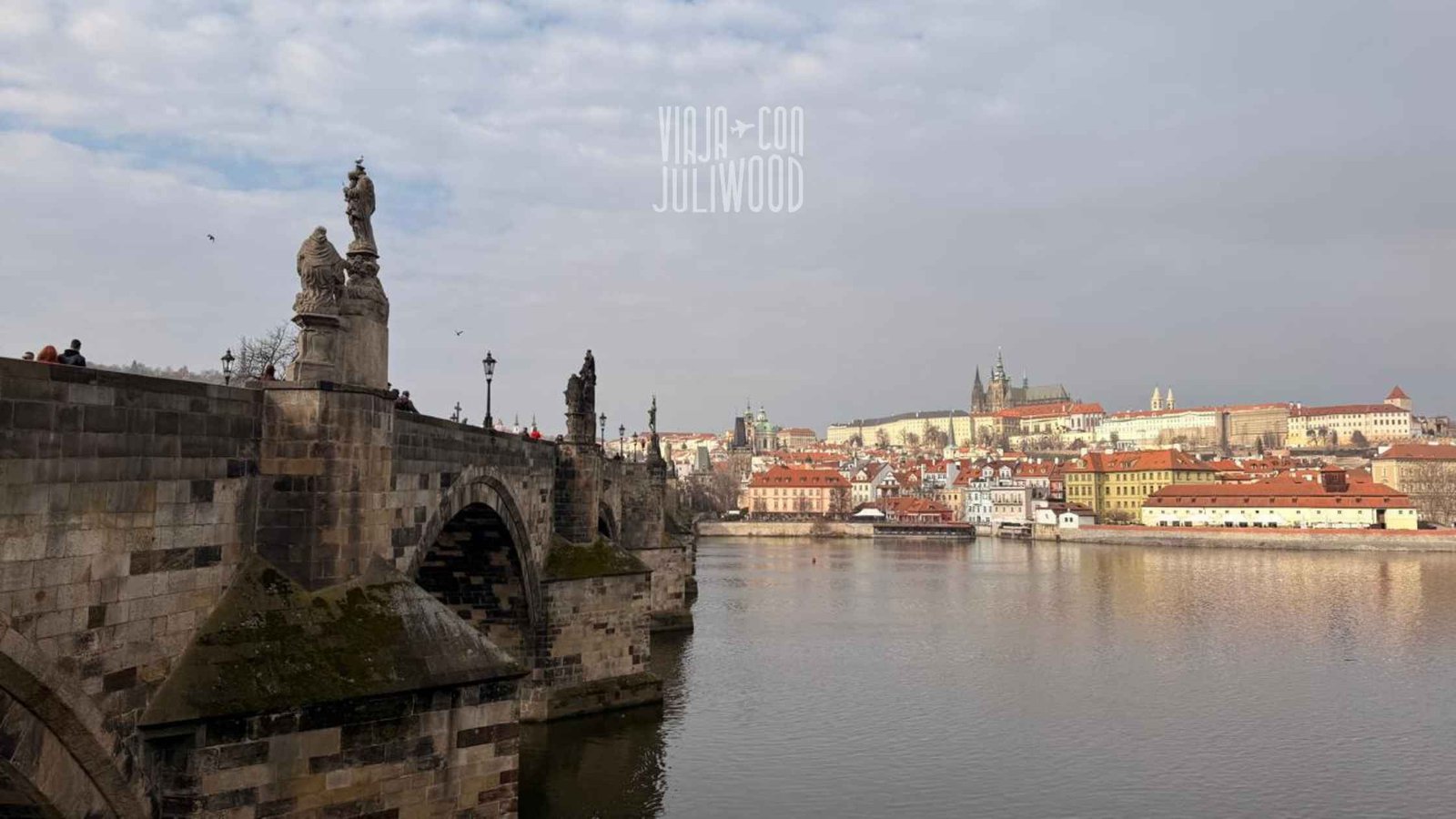Puente de Carlos en Praga con esculturas y vista al castillo y al río Moldava.