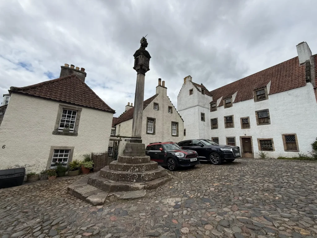 Plaza histórica de Culross con casas de piedra y calles empedradas, escenario de Cranesmuir en Outlander.